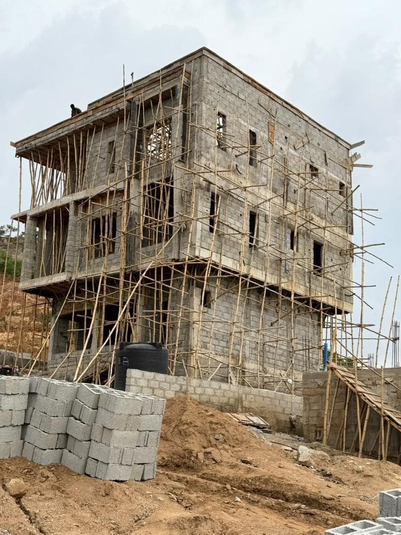 Rear elevation with blockwork complete to the top floor and the boundary wall under construction alongside